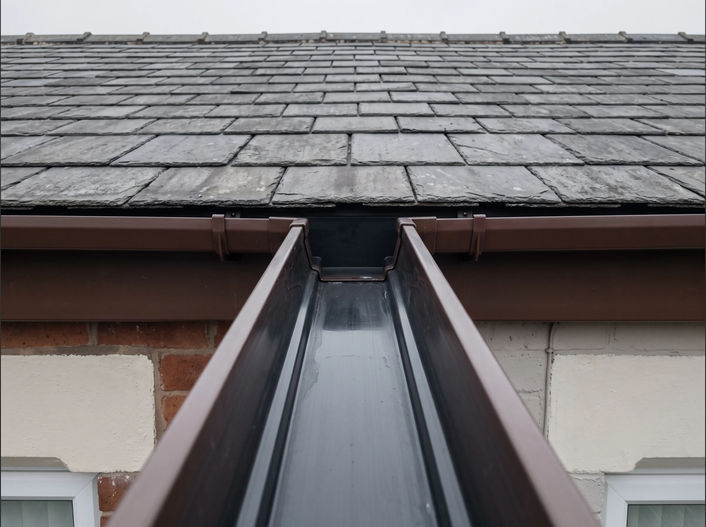The same brown uPVC gutter rinsed clean and empty after the sapling was removed
