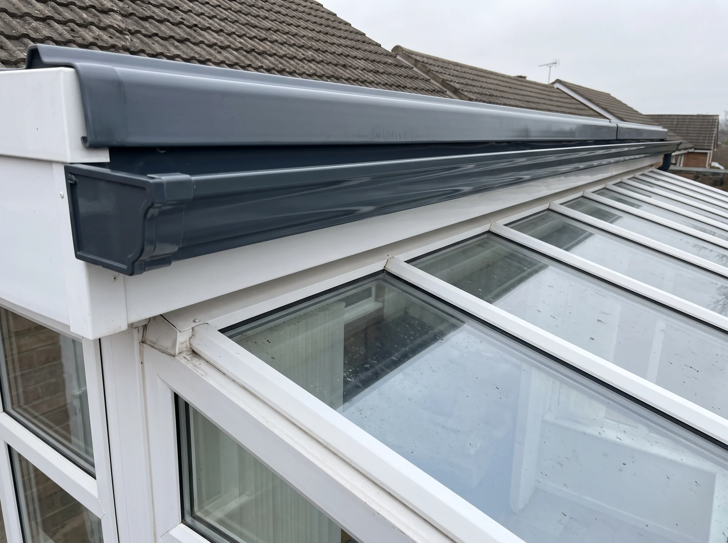 The same ogee gutter cleared to bare channel with the conservatory glass unmarked below